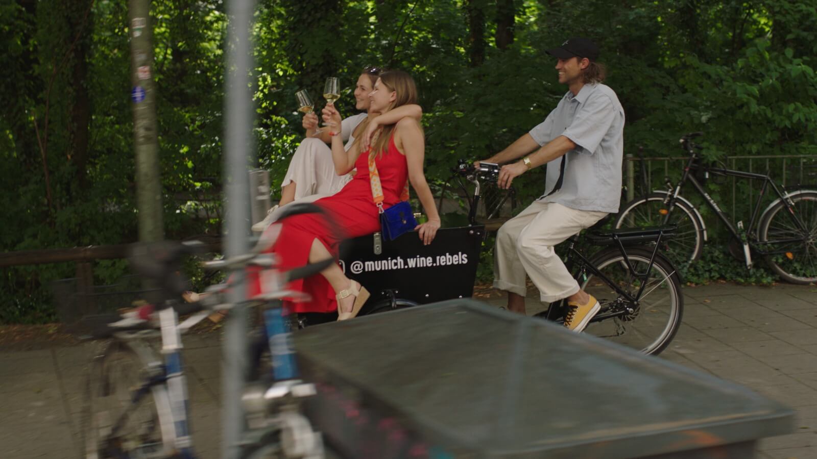 2 females sitting on wine bike with guy riding outdoor