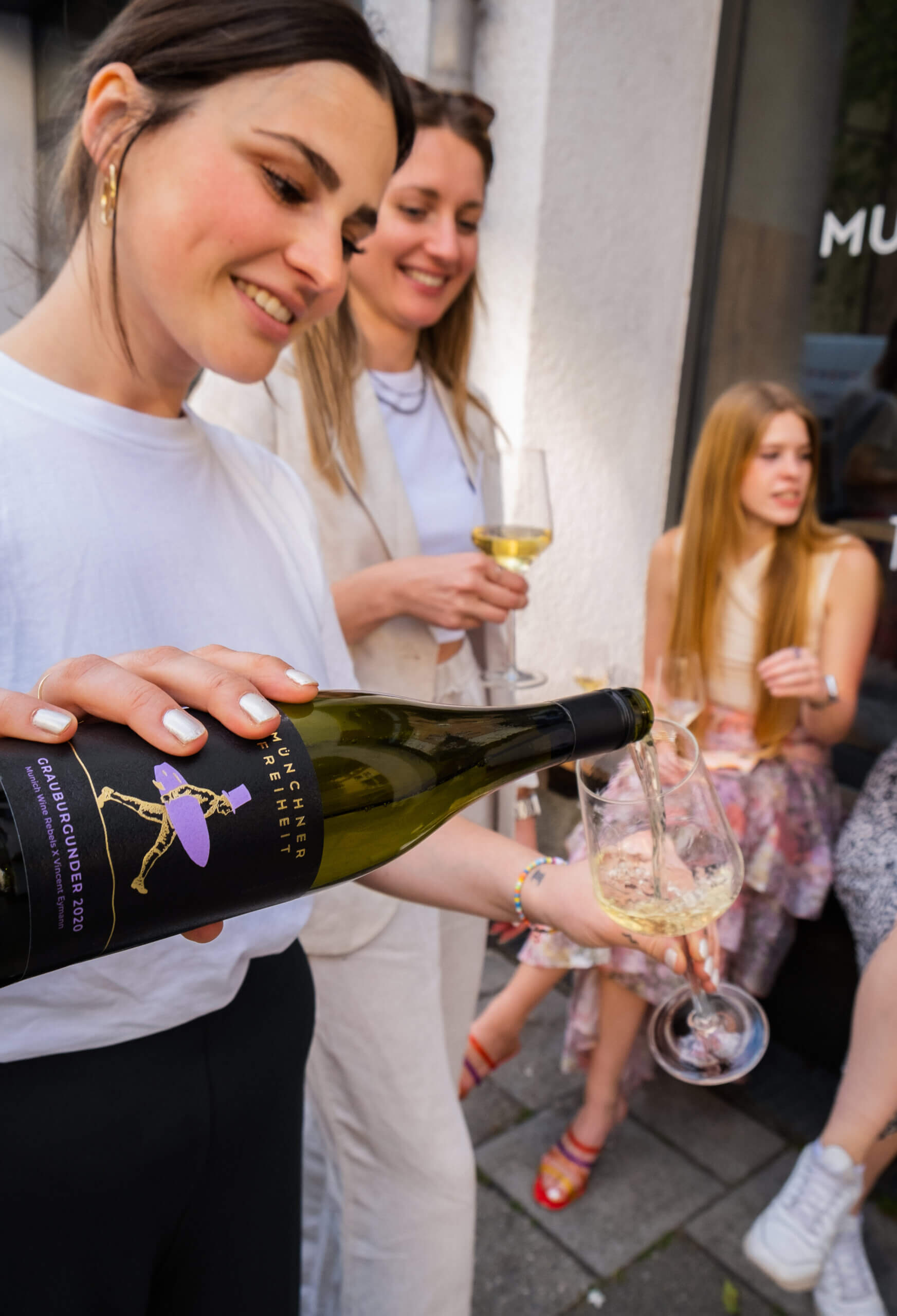 female pouring wine surrounded by people outdoor